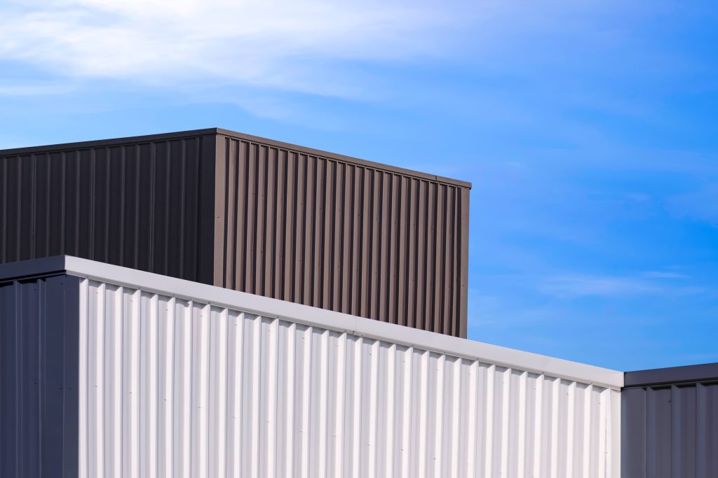 Aluminum corrugated steel industrial buildings in modern style against blue sky background, low angle and perspective side view